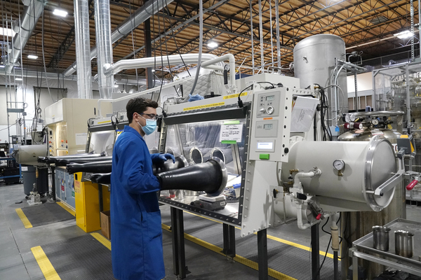 A test engineer pulls his arm out of a glove box used for processing sodium.