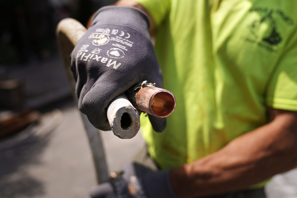 FILE - Richie Nero, of Boyle & Fogarty Construction, shows the the cross section of an original lead, residential water service line, at left, and the replacement copper line, at right, outside a home where service was getting upgraded, June 29, 2023, in Providence, R.I. As the Biden administration makes billions of dollars available to remove millions of dangerous lead water pipes that can contaminate drinking water and damage brain development in children, some states are turning down funds. (AP Photo/Charles Krupa, File)